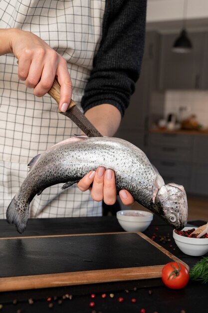 Foto gratuita vista frontale del cuoco che pulisce il pesce in cucina