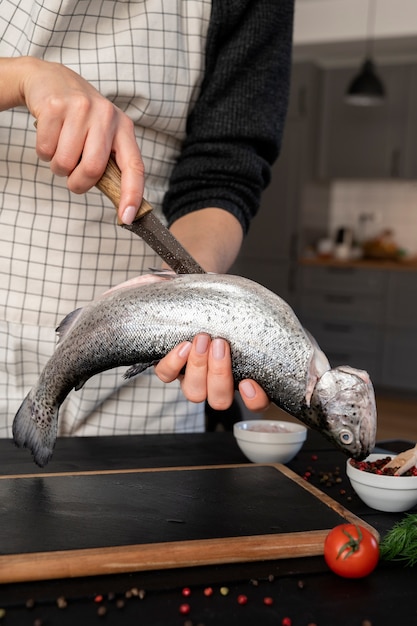 Front view cook cleaning fish in kitchen