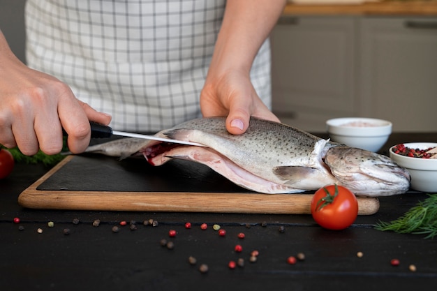 Front view cook cleaning fish in kitchen