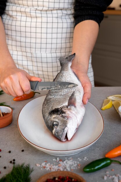 Front view cook cleaning fish in kitchen