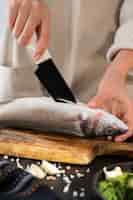 Free photo front view cook cleaning fish in kitchen