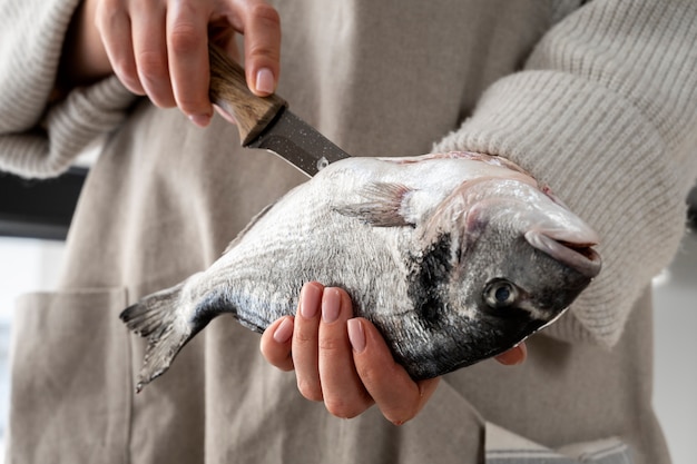 Foto gratuita vista frontale del cuoco che pulisce il pesce in cucina