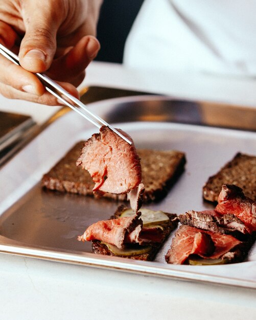 A front view cook preparing meat covering meal inside plate fry meat food meal