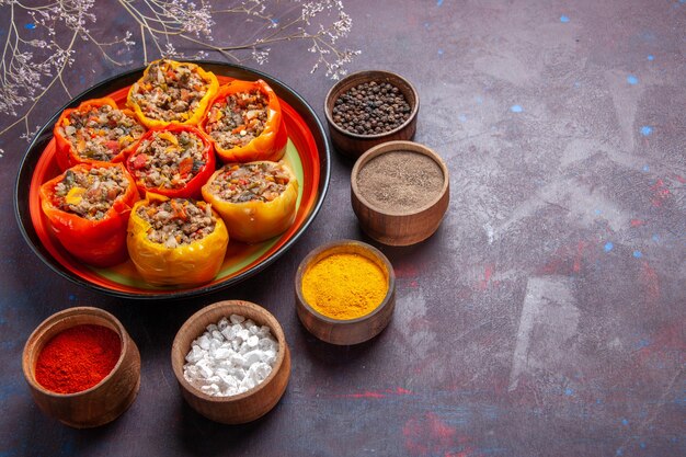 Front view cooked bell-peppers with ground meat and different seasonings on a grey surface meal dolma food vegetables beef meat