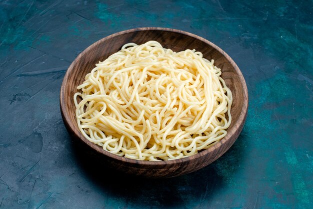 Front view cooked italian pasta inside round wooden plate on blue surface pasta italy food dinner dough meat