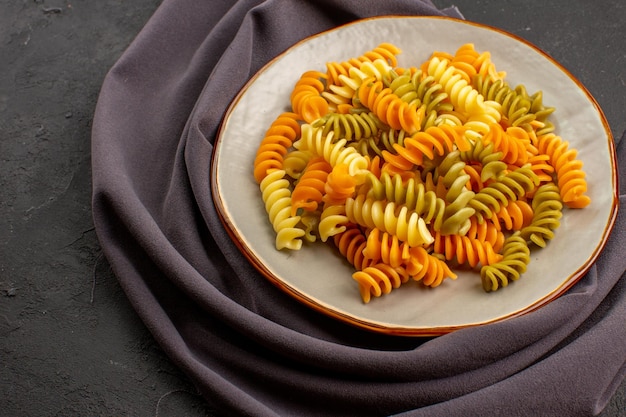 Front view cooked italian pasta unusual spiral pasta inside plate on dark space