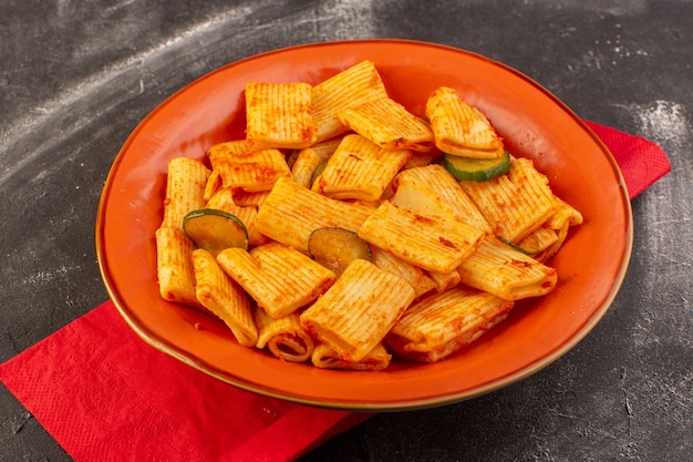 Foto gratuita una vista frontale ha cucinato la pasta italiana con salsa di pomodoro e cetriolo all'interno del piatto sulla superficie scura