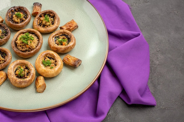 Front view cooked mushrooms inside plate on purple tissue and on a dark background dish meal cooking mushrooms dinner