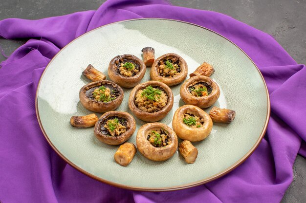 Front view cooked mushrooms inside plate on purple tissue and on dark background dish meal cooking mushrooms dinner