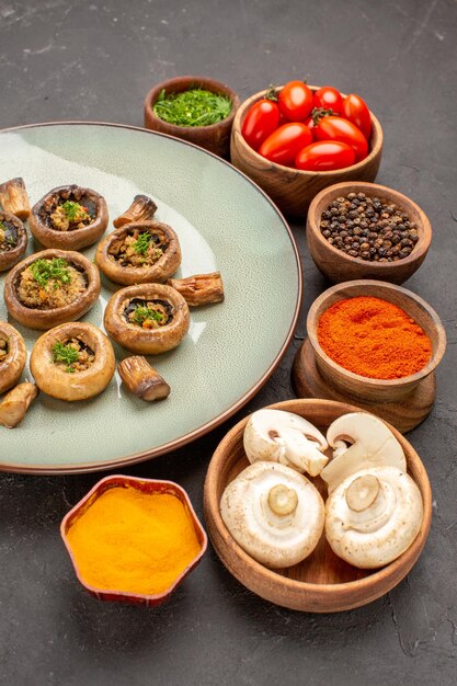 Вид спереди приготовленные грибы с помидорами и приправами на темном столе, блюдо, ужин с грибами
