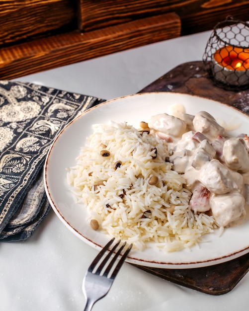 Front view cooked rice along with beans and meat slices inside white plate on the wooden surface