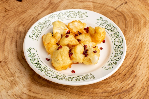 Front view of cooked sliced cauliflower inside plate on the cream wooden desk