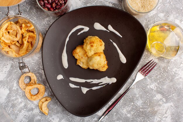 Front view of cooked sliced cauliflower with oil and beans on the light white wall