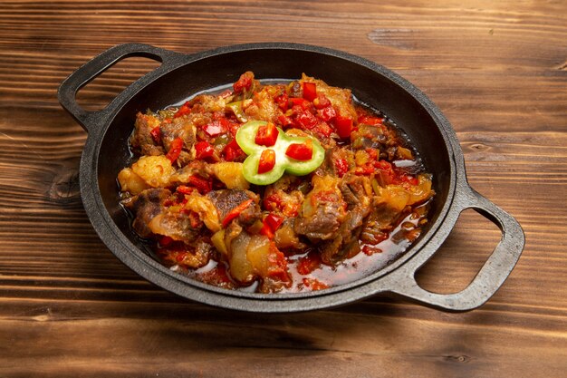 Front view cooked vegetable meal inside pan on the brown wooden desk