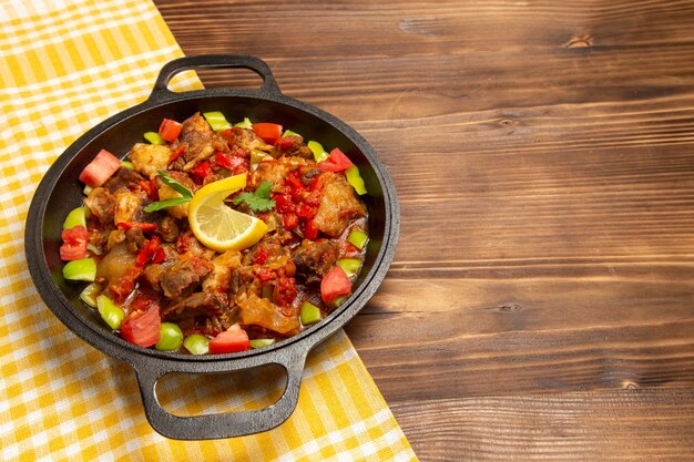 Front view cooked vegetable meal with meat and sliced bell peppers on brown desk