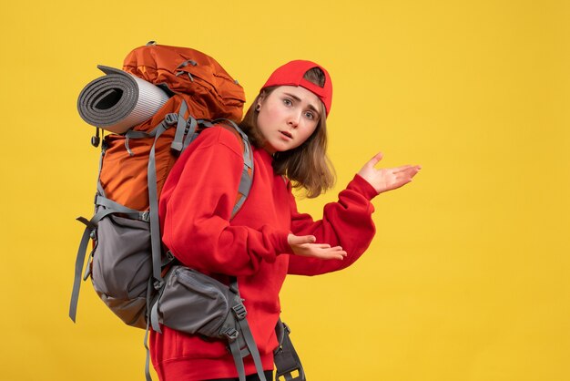 Front view cool female traveler with backpack showing something