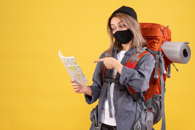Front view of cool traveler girl with black mask and backpack looking at map