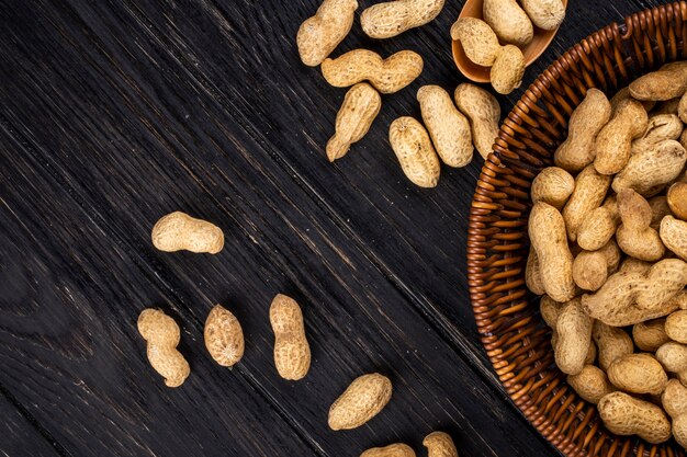 Free photo front view copy space peanuts in shell in a basket on a black wooden table