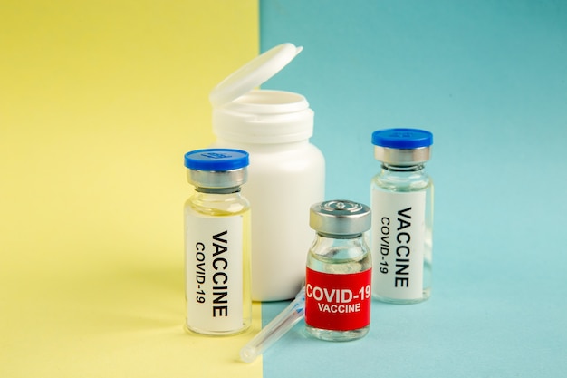 黄青色の背景に注射された正面図のコロナウイルスワクチンラボ病院ウイルスコビッドサイエンス健康パンデミックカラードラッグ