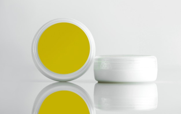 Foto gratuita vaso cosmetico vista frontale per crema un vaso bianco con un coperchio giallo