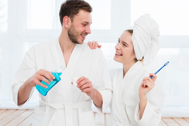 Front view of couple in bathrobes with mouthwash and toothbrush