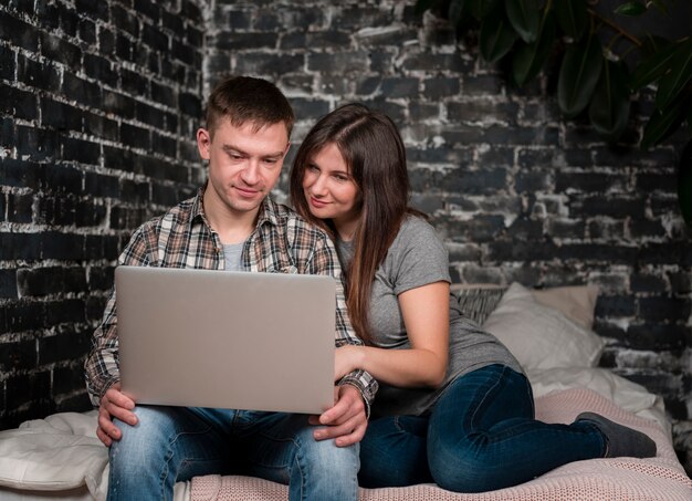 Front view of couple in bed looking at laptop