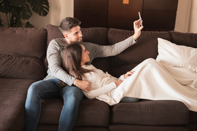 Front view couple on couch taking selfie