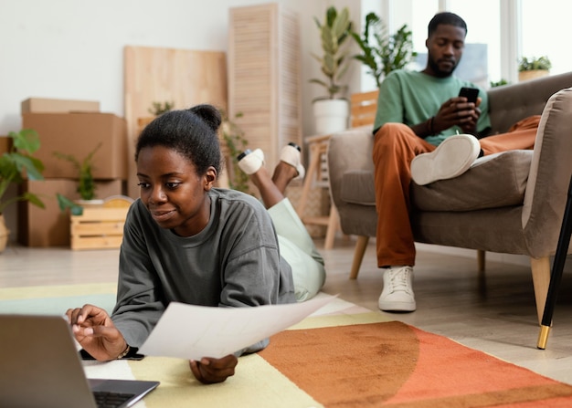 Front view of couple on the floor making plans to redecorate home with laptop