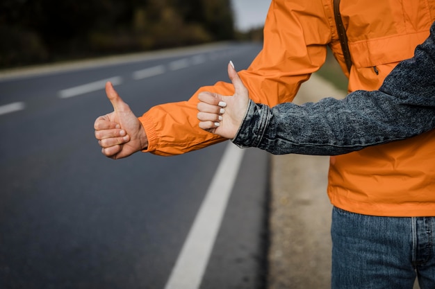 Free photo front view of couple hitchhiking while on a road trip