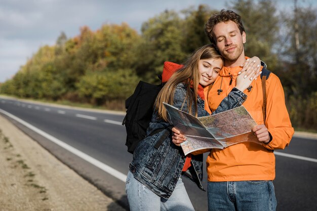 Front view of couple holding map and sitting along the road