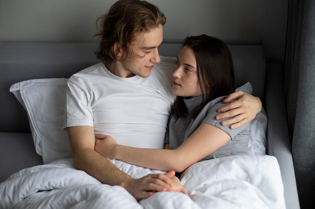 Front view of couple hugging in bed