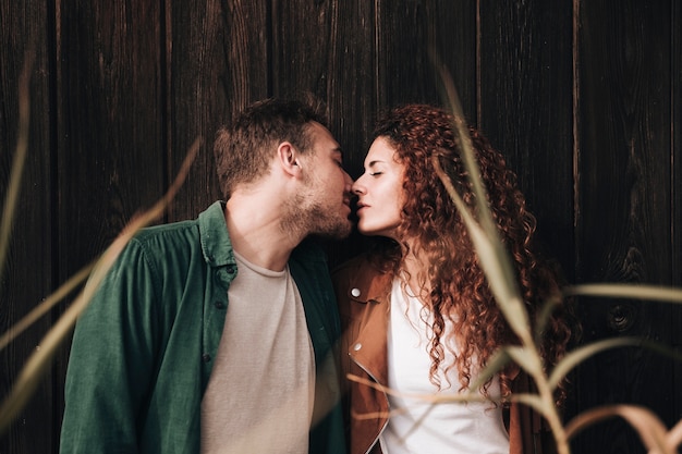 Пара вид спереди поцелуи с деревянными фоне