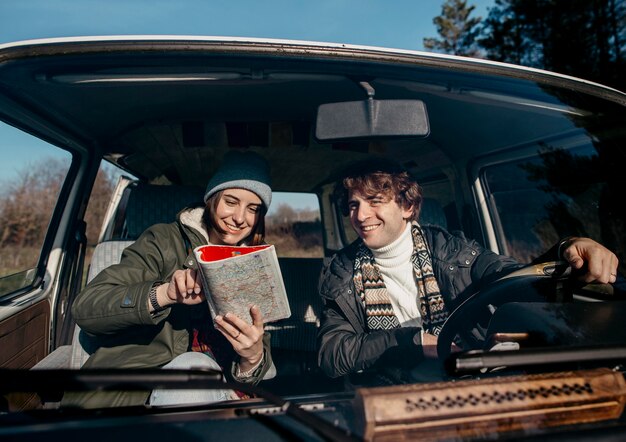 Front view couple looking at a map while road tripping