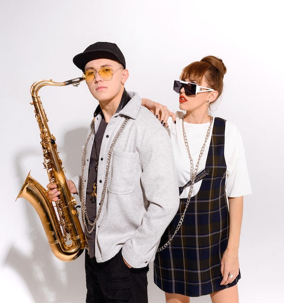 Front view of couple of musician wearing in stylish outfit with accessories posing against white background in studio Side view