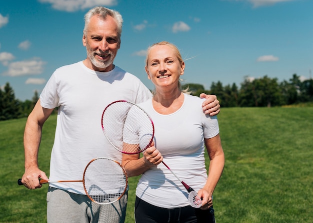 Бесплатное фото Пара вид спереди позирует с теннисными ракетками