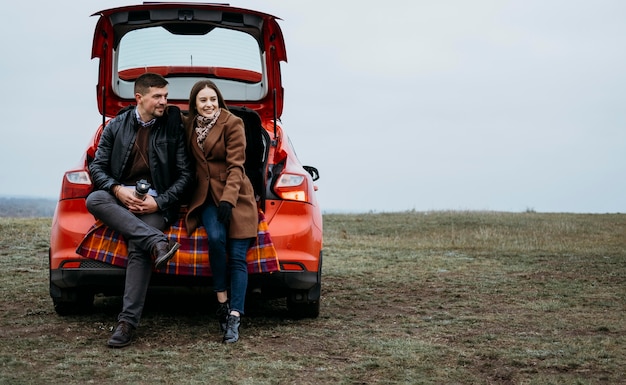 Front view of couple sitting in the car's trunk with copy space