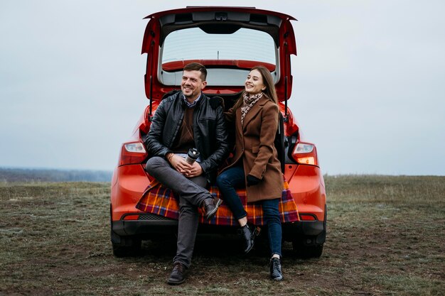 Front view of couple sitting in the car's trunk