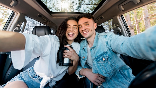 Foto gratuita coppia vista frontale prendendo selfie in auto