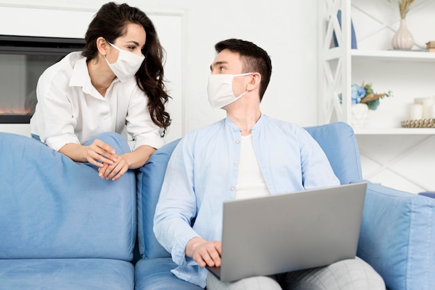 Front view of couple with face masks at home