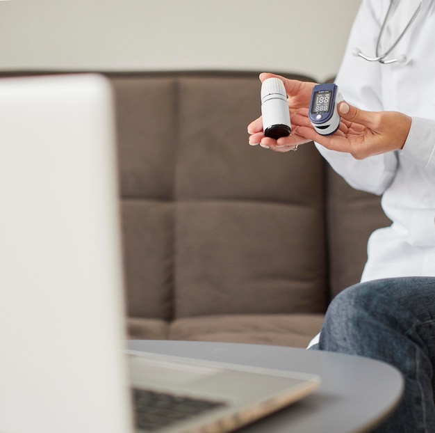 Front view of covid recovery center female doctor holding oximeter and pills