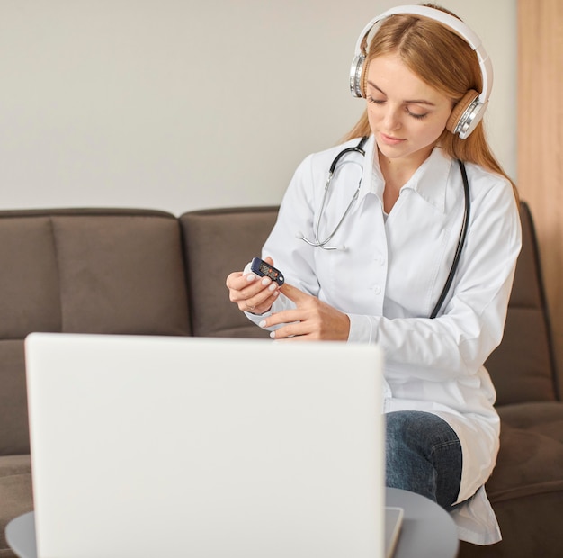 Front view of covid recovery center female doctor with headphones demonstrating how to use oximeter