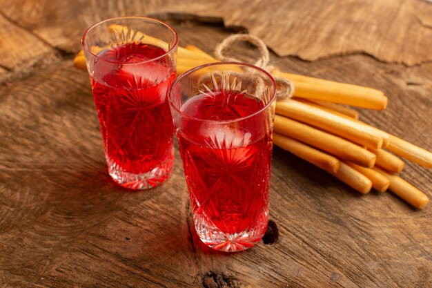 Front view of cranberry juice red colored with stick crackers on the wooden surface