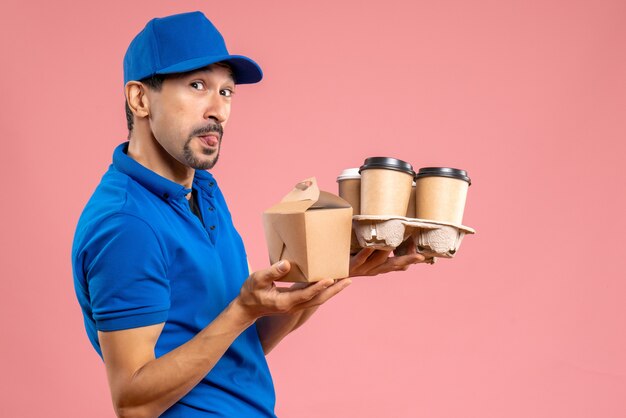 Front view of crazy emotional male delivery guy wearing hat holding orders