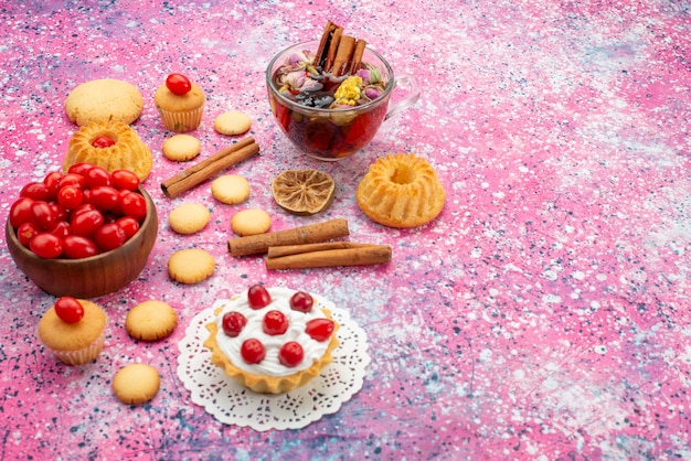 Front view cream cake with fresh red cranberries along with cinnamon cookies and tea on the bright desk biscuit sweet fruit