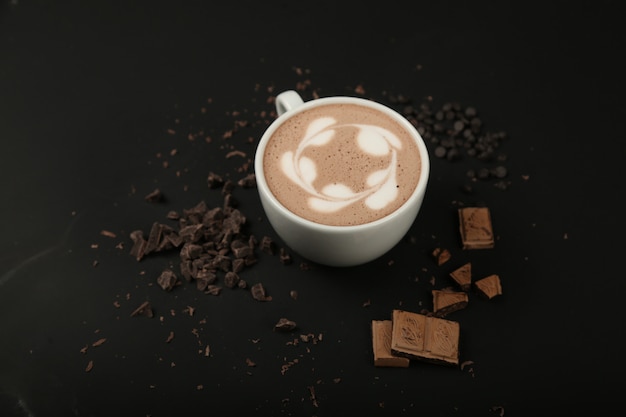 Tazza di cappuccino con cioccolato sulla superficie nera vista frontale