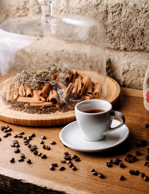 Front view cup of coffee along with coffee seeds and cinnamon on the bright desk