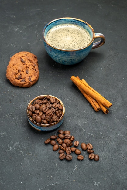 Free photo front view a cup of coffee bowl with coffee seeds cinnamon sticks biscuits on dark