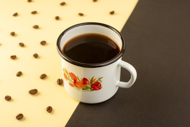 A front view cup of coffee with brown coffee seeds on the yellow-dark surface drink coffee grain