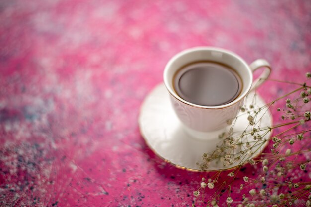 ピンクの机の上の皿の上のカップの中のお茶の正面図