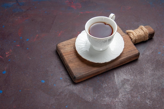 Вид спереди чашка чая внутри стеклянной чашки с тарелкой на темном пространстве